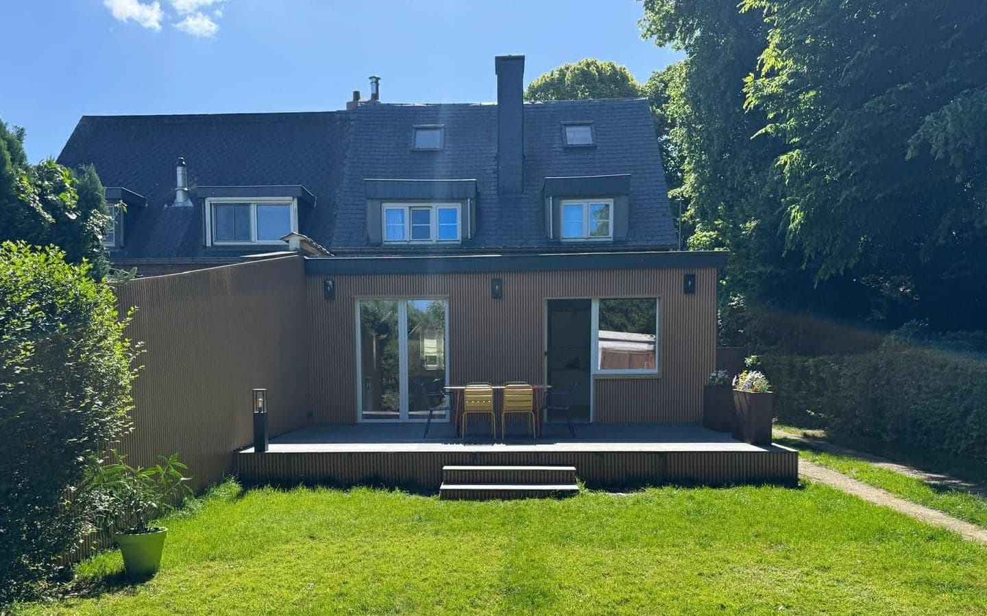 Terrasse en bois à l'arrière d'une maison, devant une pelouse entretenue