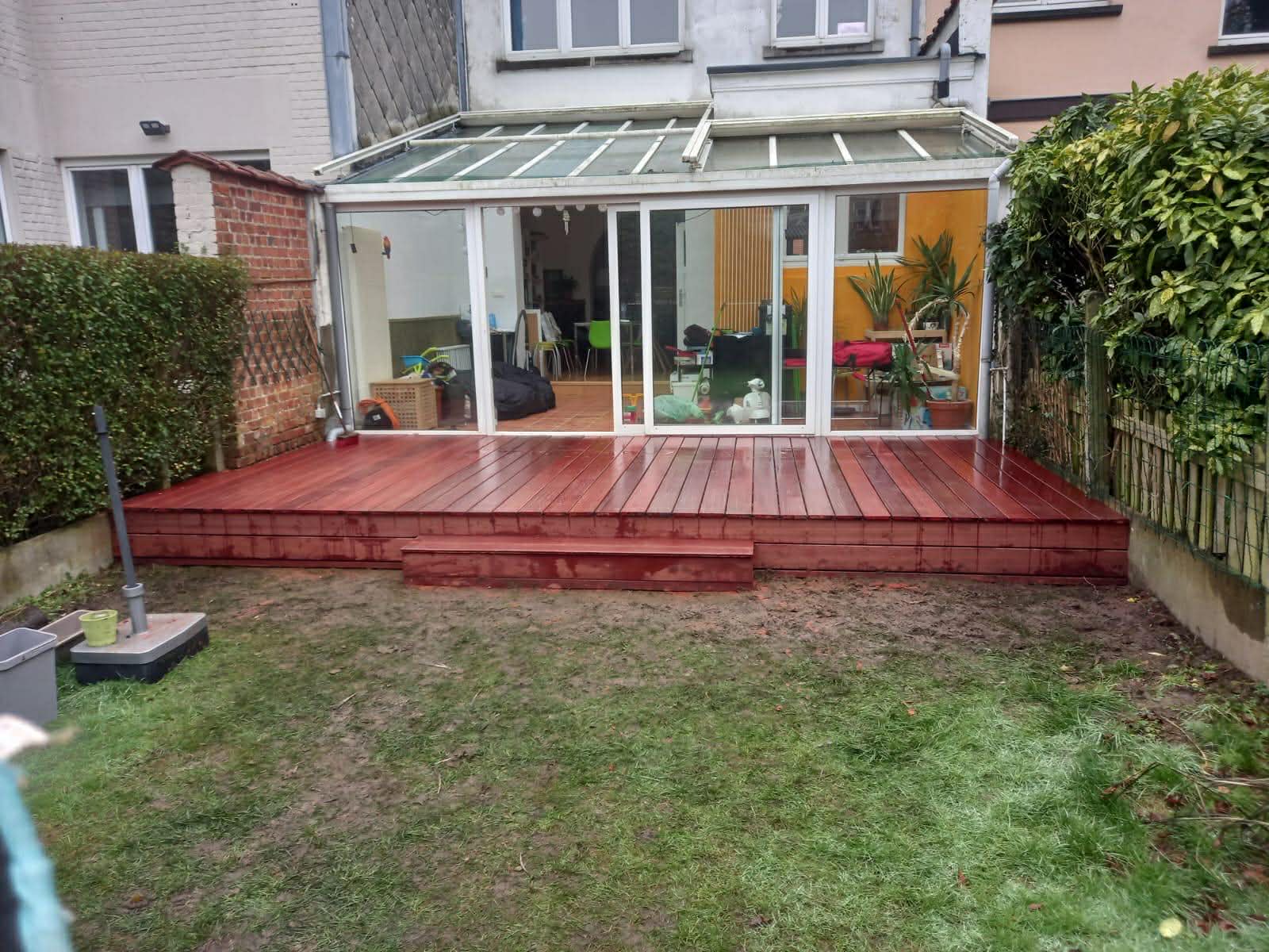 Terrasse en bois devant une véranda, avec pelouse refaite